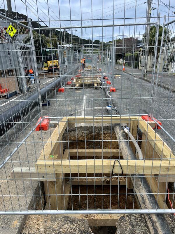 Square holes reinforced with wood and surrounded by silver fences with pipes running along the road on Owen St, Newtown. 