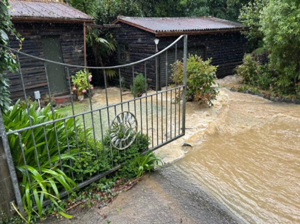 Floodwaters rushing down a driveway towards a garage and house